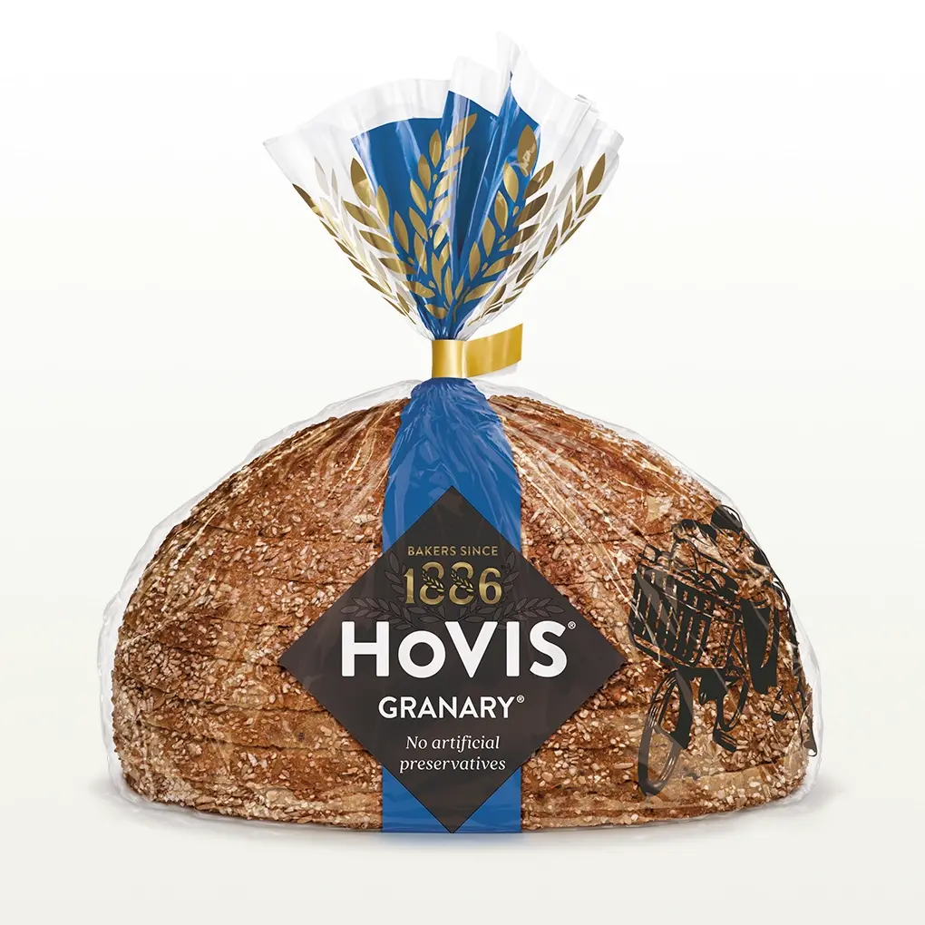 Hovis Granary Half Cob bread on a white backdrop with a subtle shadow, featuring packaging decorated with a dark blue stripe and golden wheats.