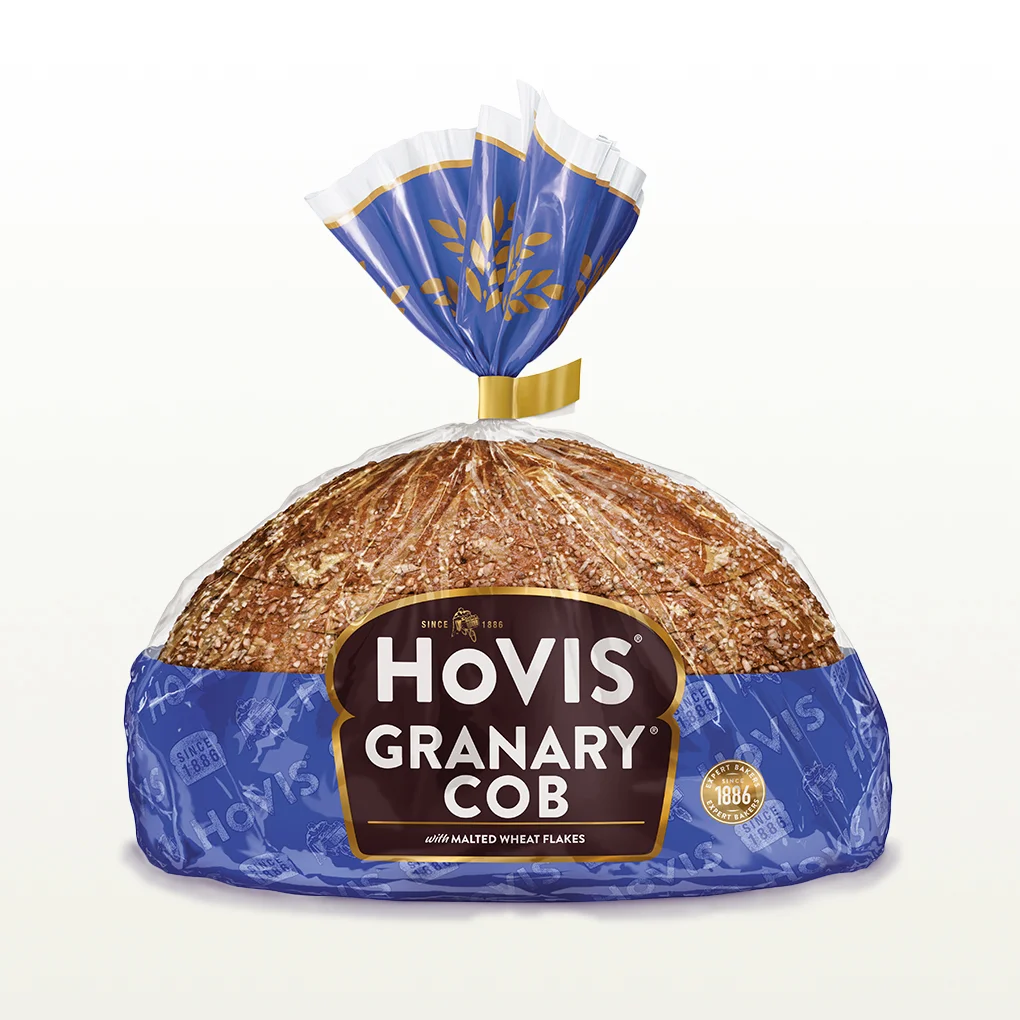 Hovis Granary Half Cob bread on a white backdrop with a subtle shadow, featuring packaging decorated with a dark blue stripe and golden wheats.