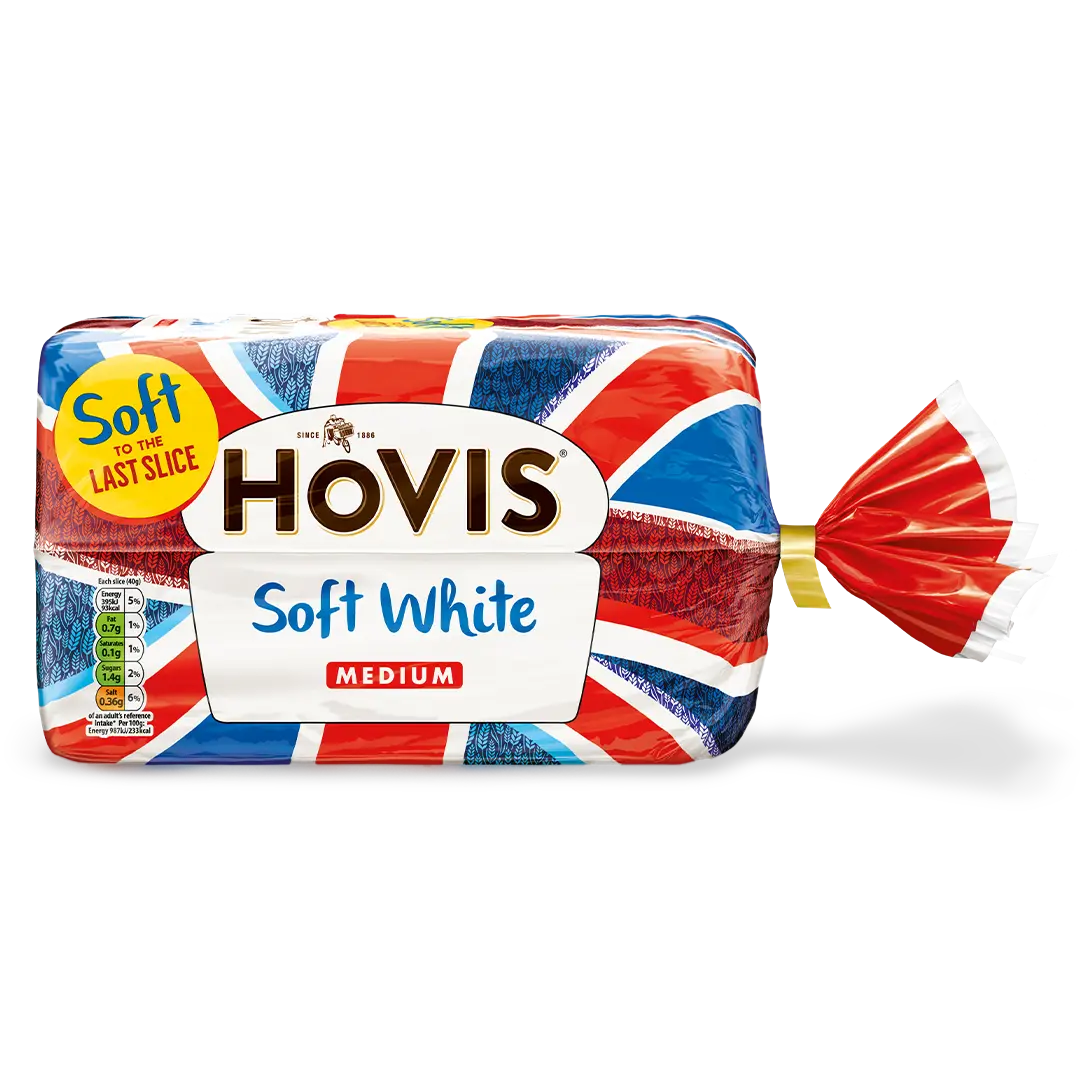 Hovis Soft White Medium Sliced bread with a subtle shadow under it. The packaging features a Union Jack pattern and a yellow label reading 'Soft to the Last Slice.'