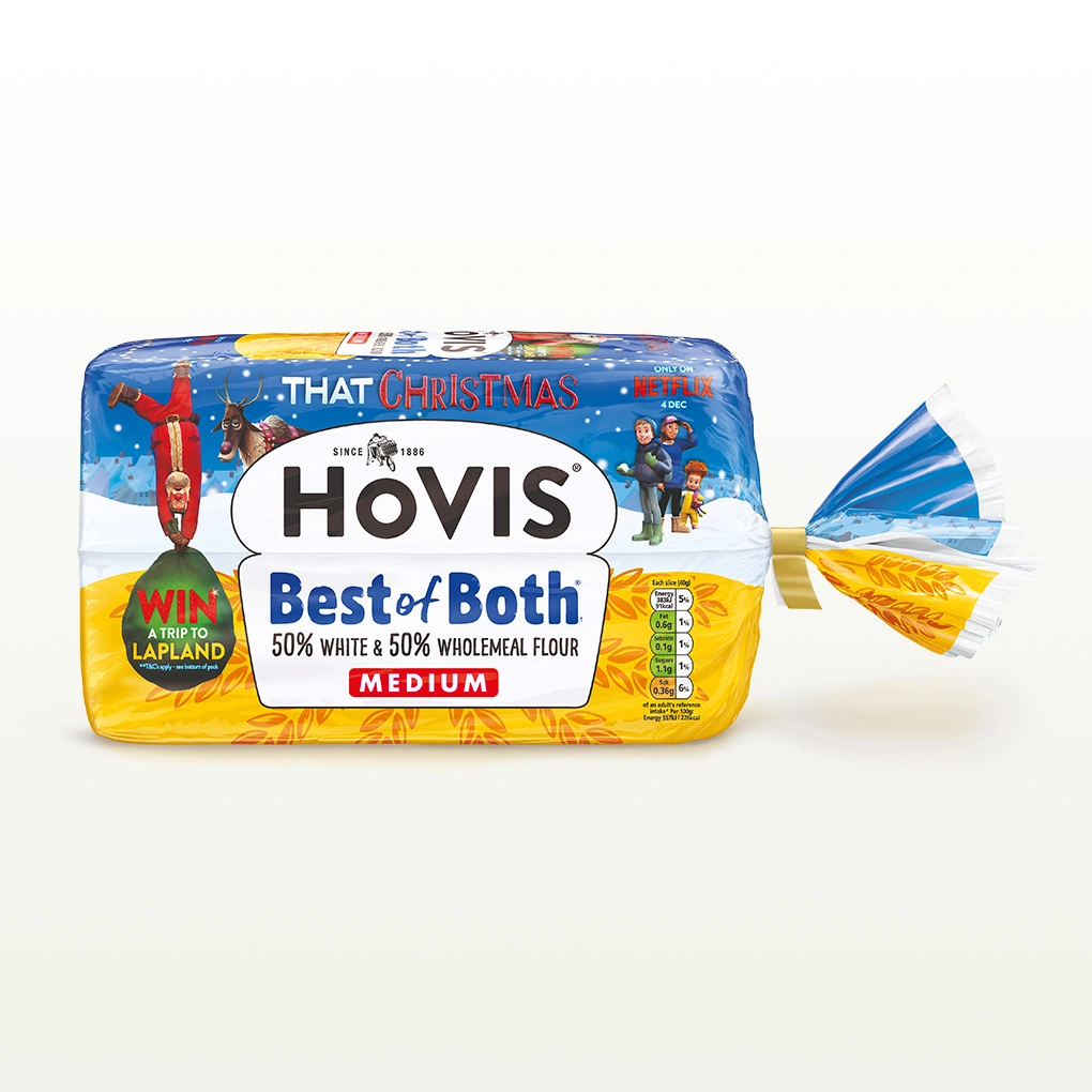 A Hovis Best of Both loaf thickly sliced sits within a white back drop with a subtle shadow below the bread. This particular packaging has Christmas elements on it as well such as a Santa Claus. 