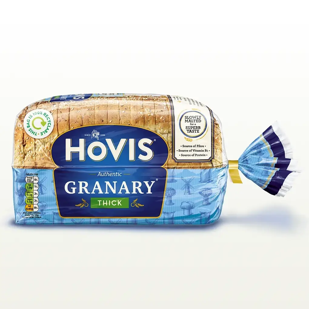 Hovis Granary Thick Sliced bread on a white backdrop with a subtle shadow. The packaging is half transparent and half blue, decorated with images of mills, a chefs hat, flour and wheat.