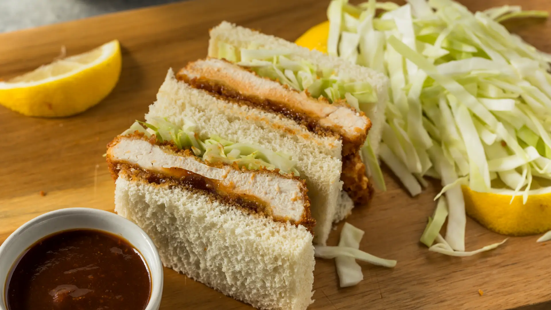 Crispy breaded chicken and shredded cabbage sandwiched between two crustless slices of white bread, cut into smaller rectangles.