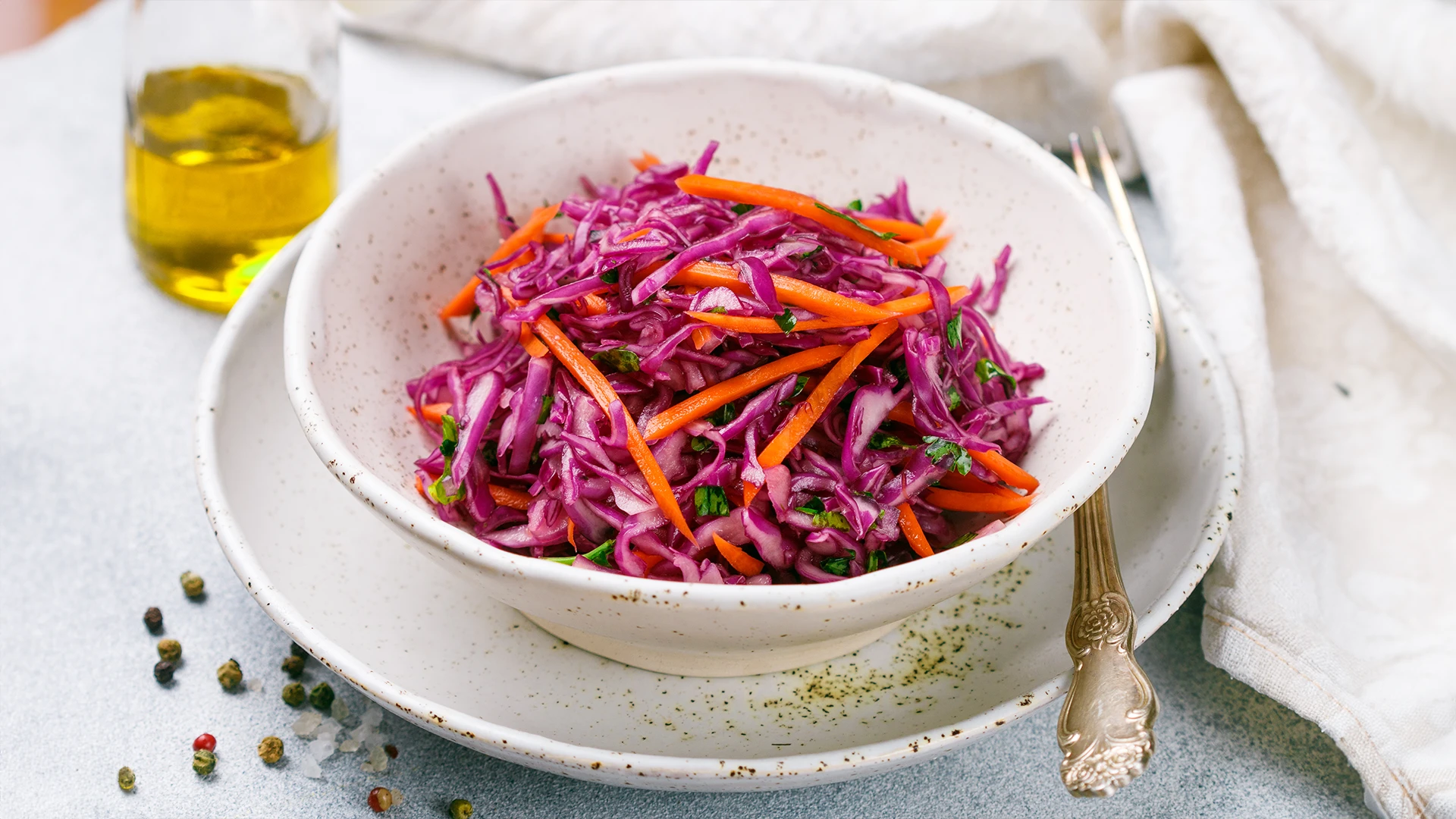 A bowl filled with shredded carrots, red cabbage, and chopped parsley.