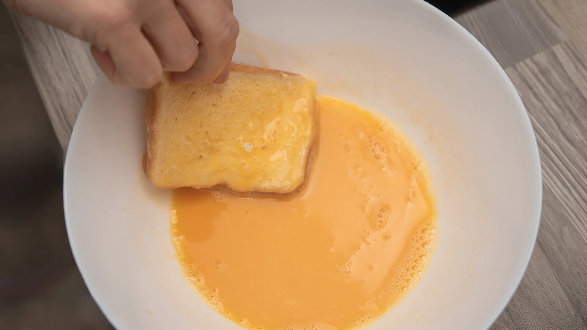 Peanut butter sandwiches being dipped in an egg wash.