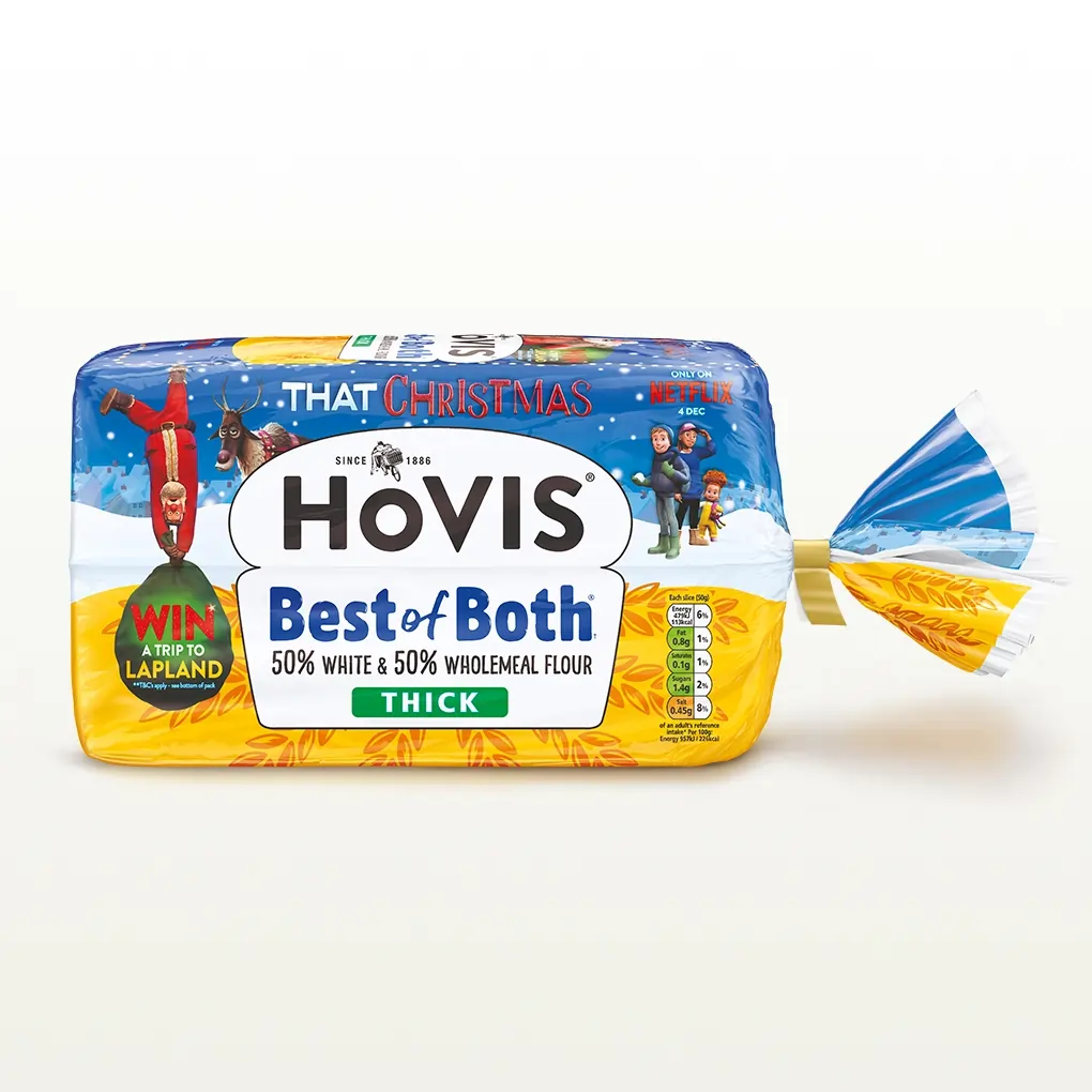 A Hovis Best of Both loaf thickly sliced sits within a white back drop with a subtle shadow below the bread. This particular packaging has Christmas elements on it as well such as a Santa Claus. 