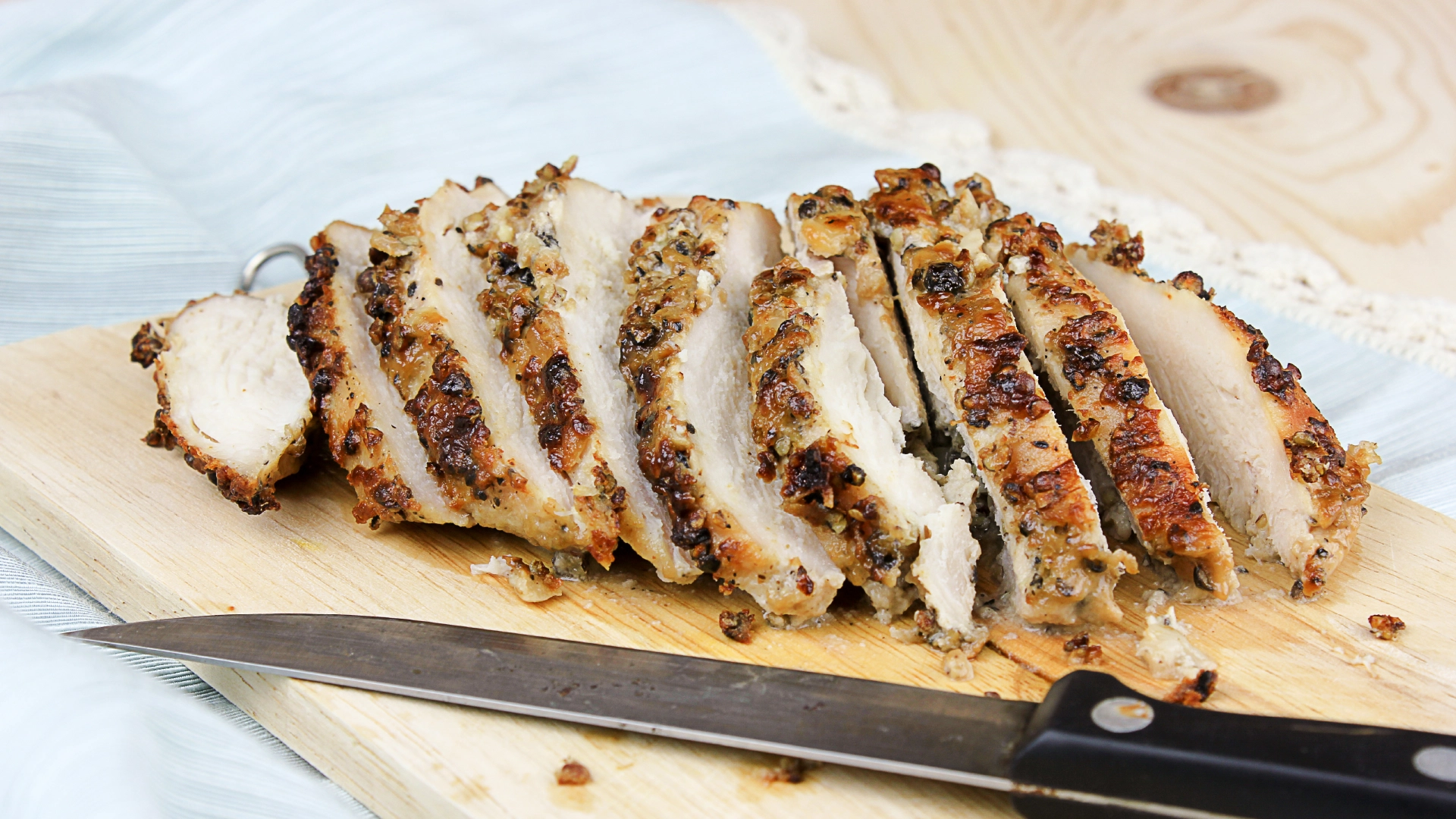 Sliced chicken on a wooden chopping board.