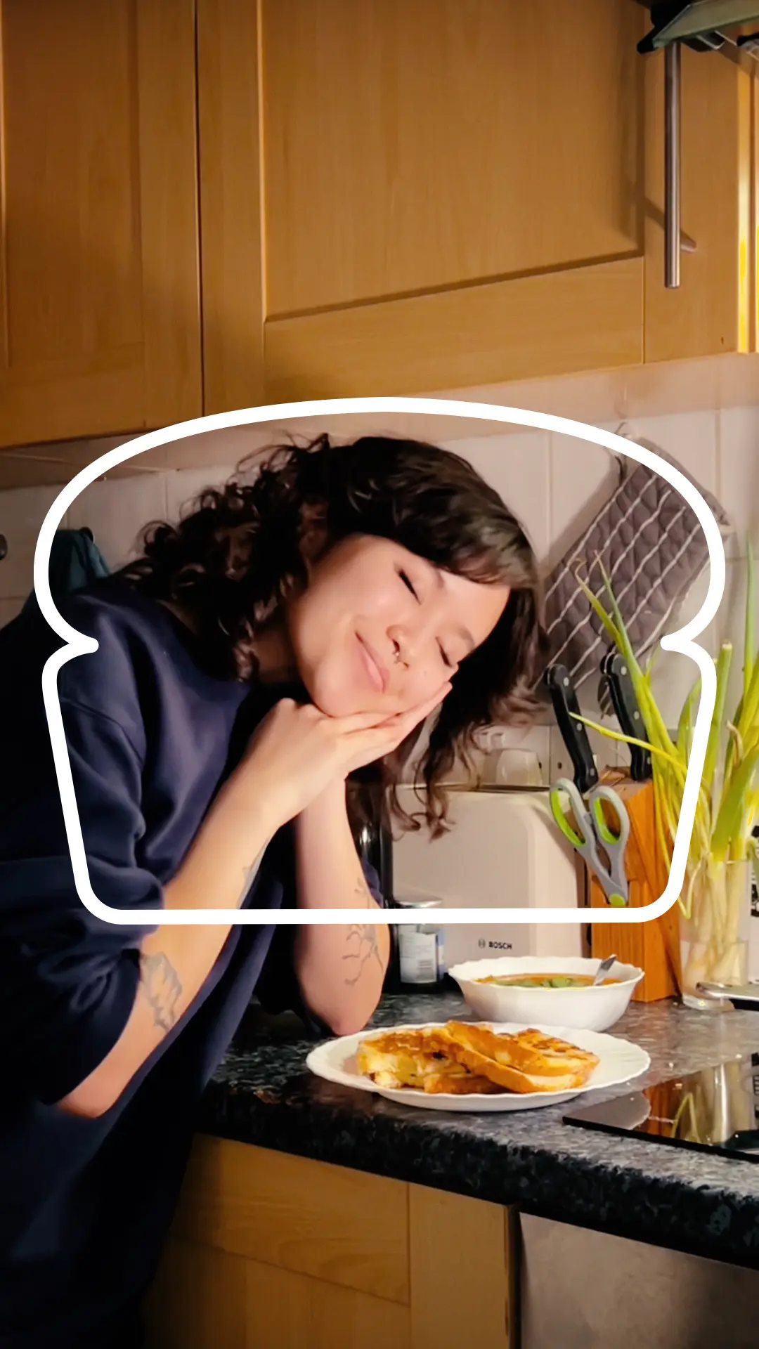 A cheese toastie rests on a white plate. Someone has their hands near their face, pretending to be asleep.