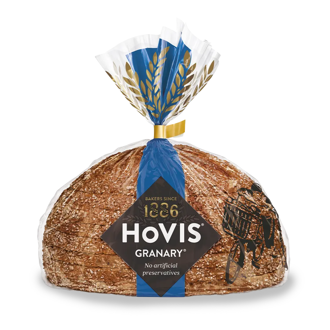 Hovis Granary Half Cob bread with a subtle shadow under it, featuring packaging decorated with a dark blue stripe and golden wheats.