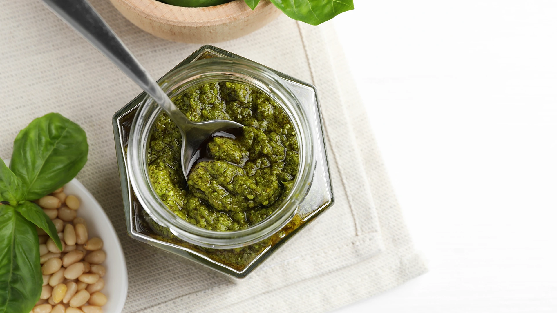 A glass jar filled with green pesto.