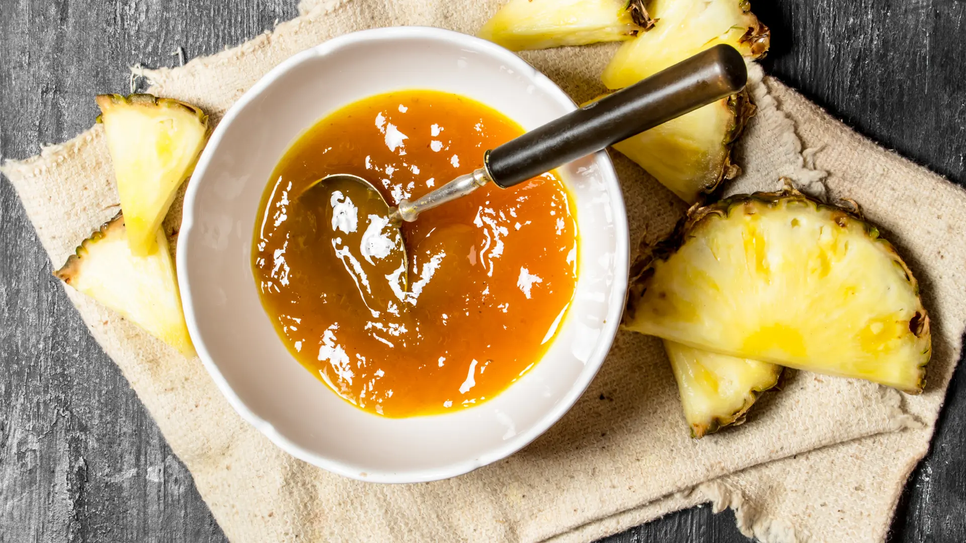 A top-down view of a bowl of pineapple jam with a spoon.