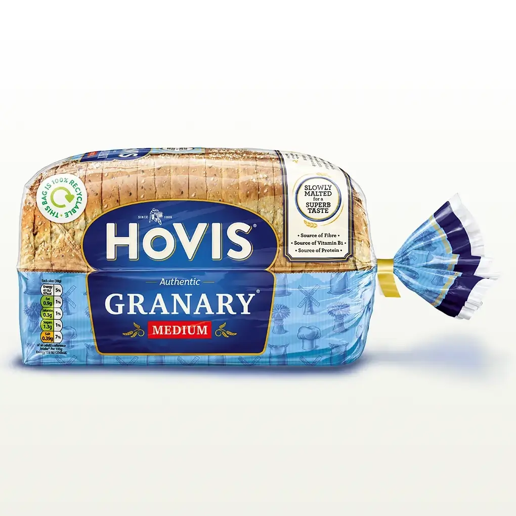 Hovis Granary Medium Sliced bread on a white backdrop with a subtle shadow. The packaging is half transparent and half blue, decorated with images of mills, flour and wheat.