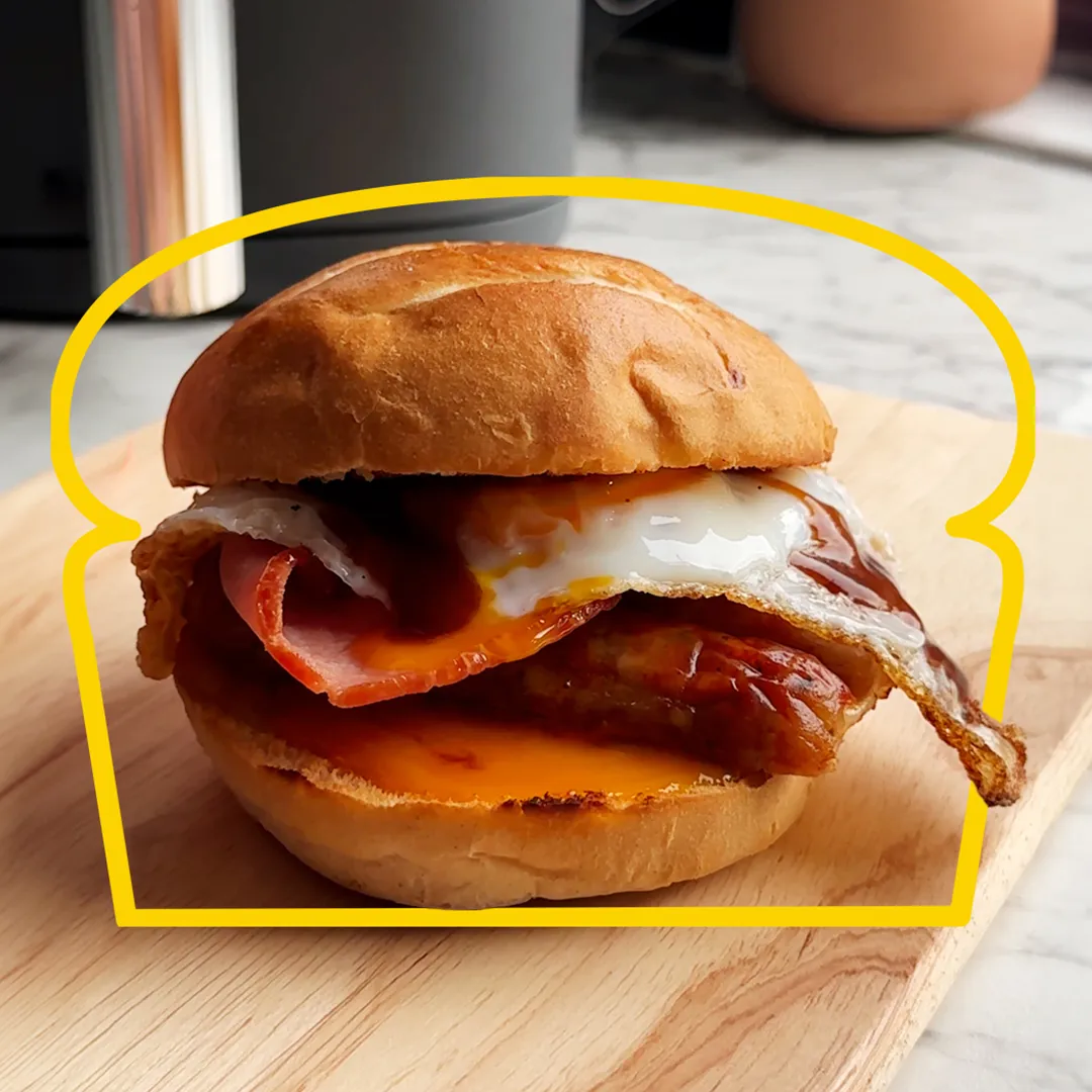 A delicious egg, bacon and sausage bun sits on a kitchen counter top