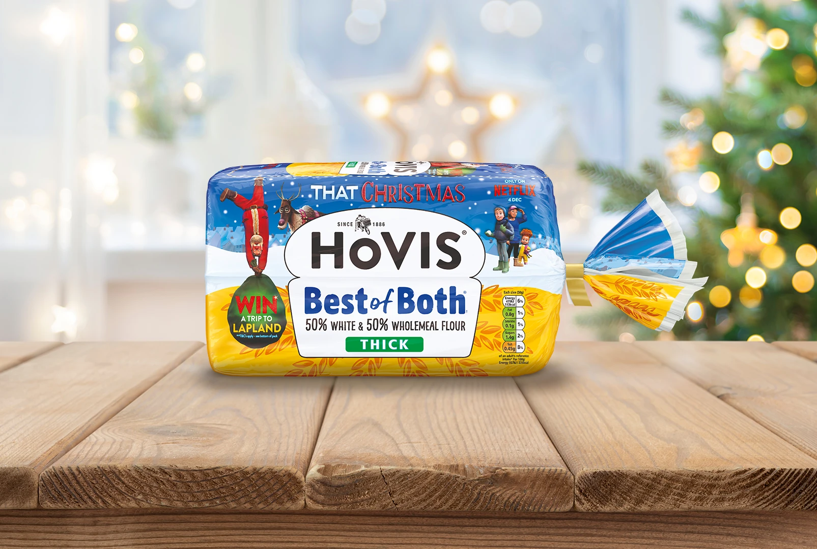 A Hovis best of both loaf sits on top of a table with christmas tree lights and other christmas decorations behind it