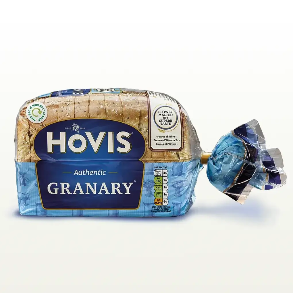 Hovis Granary 400g bread on a white backdrop with a subtle shadow. The packaging is half transparent and half blue, decorated with images of mills, flour and wheat.