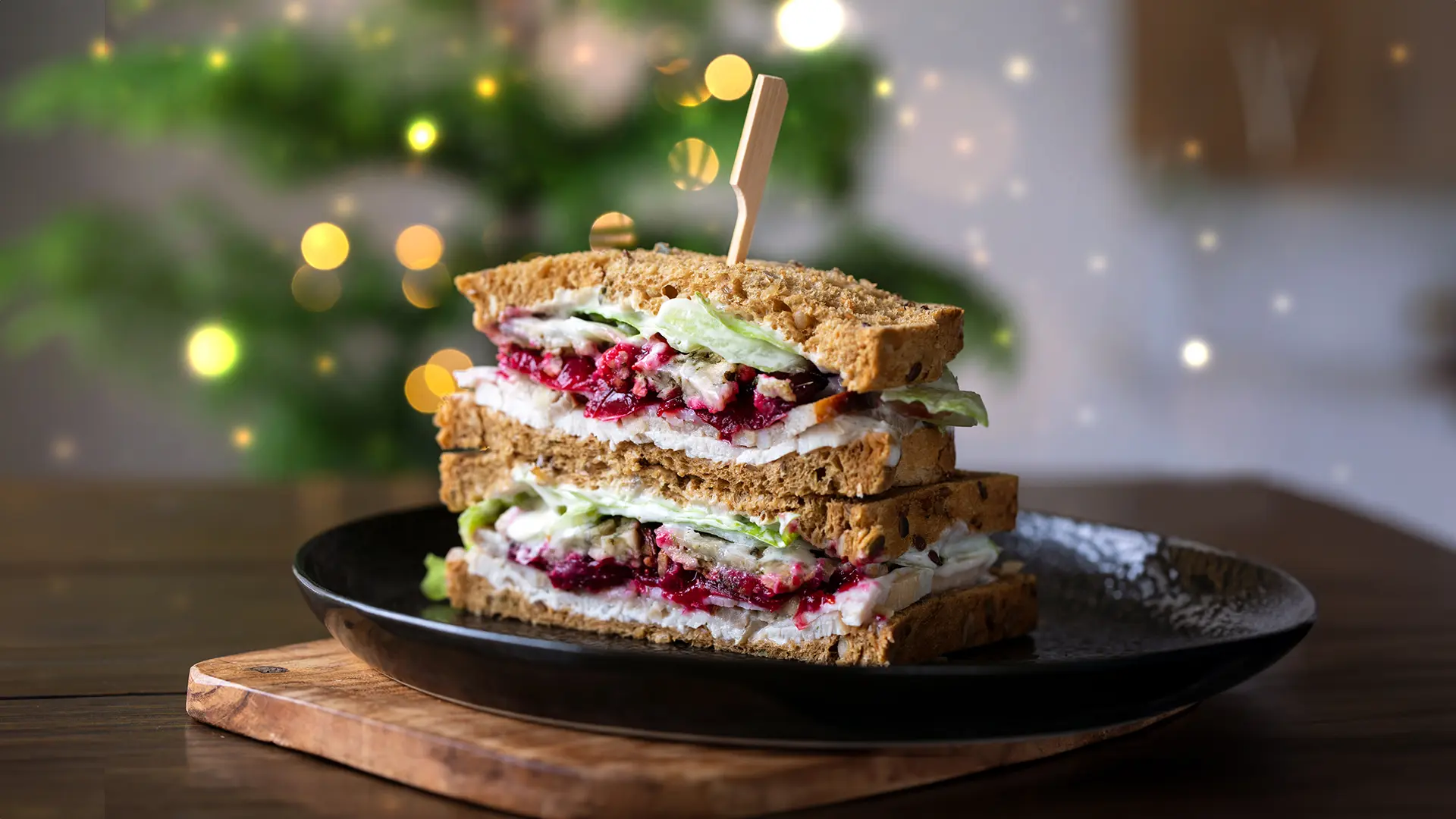 A Nimble® Wholemeal sandwich filled with thin slices of leftover turkey, lettuce, a few slices of cucumber, tomato and mayonnaise, with some Christmas lights.