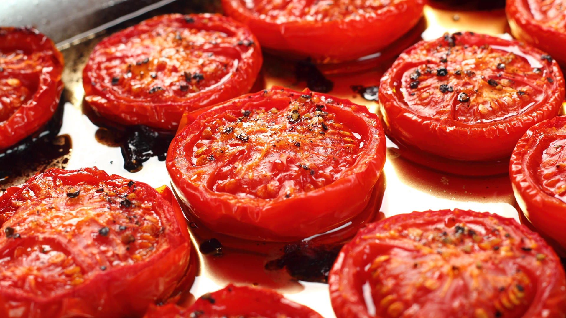 Halved tomatoes, slightly roasted, in a metal tray.