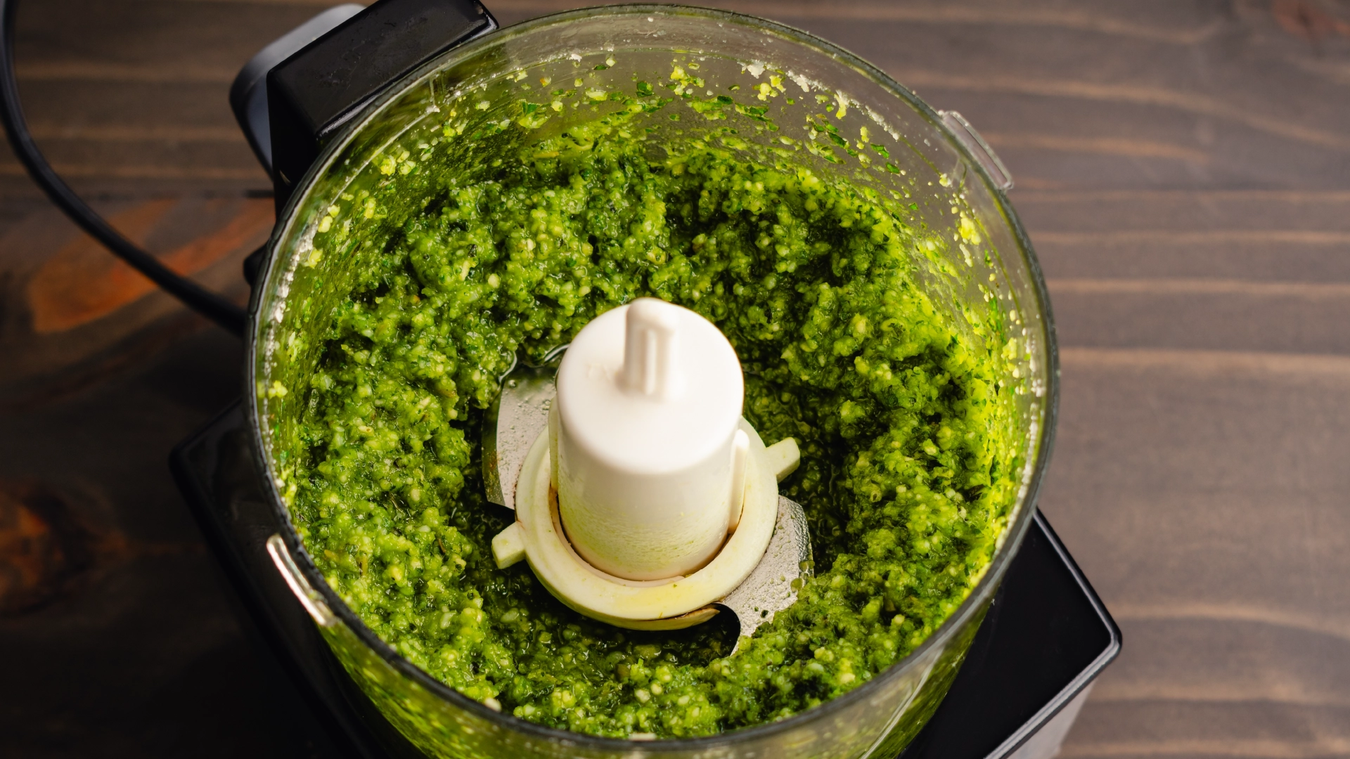 Green pesto inside a round food processor.