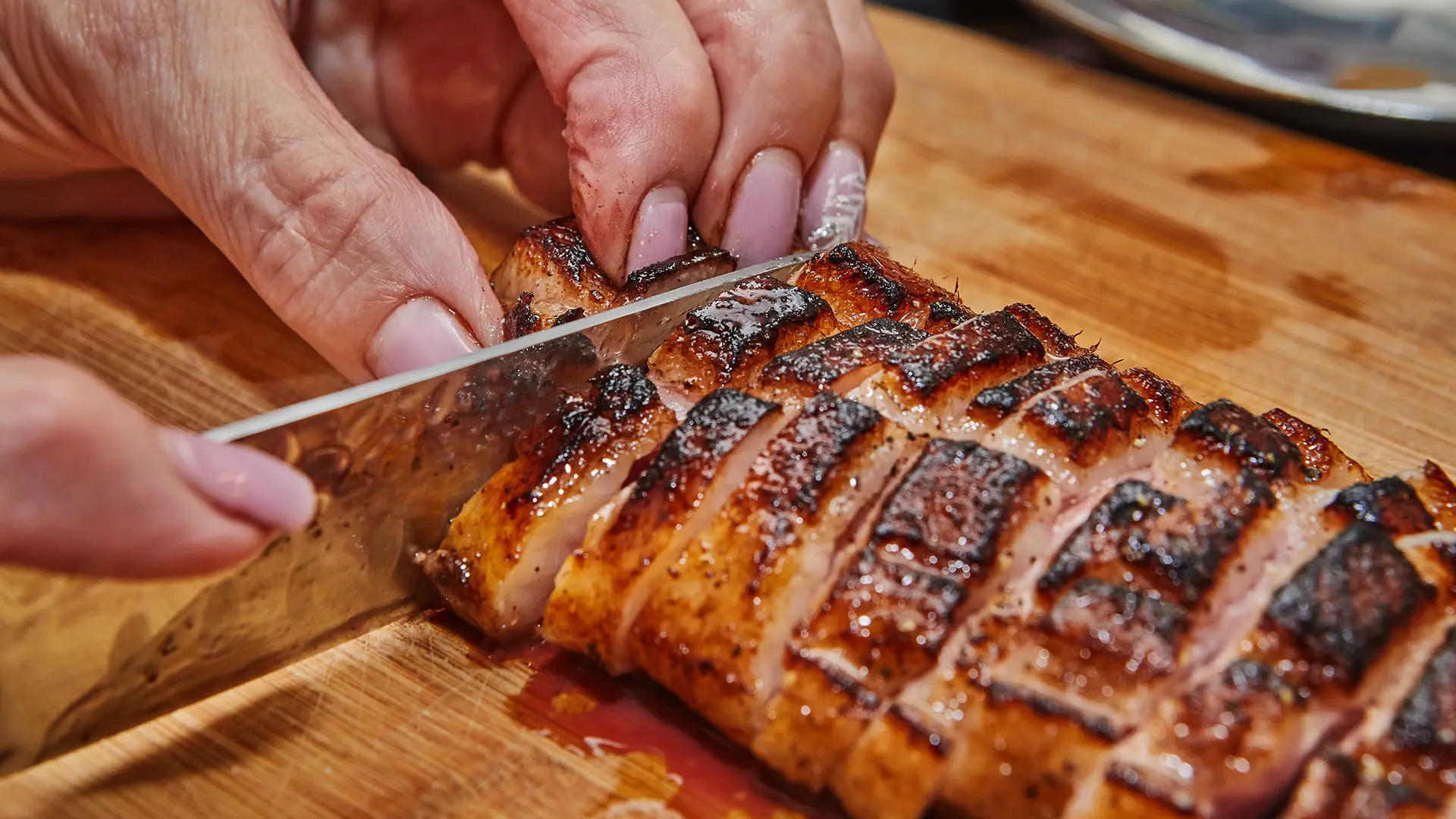 Grilled and glazed pork strips being sliced into pieces.