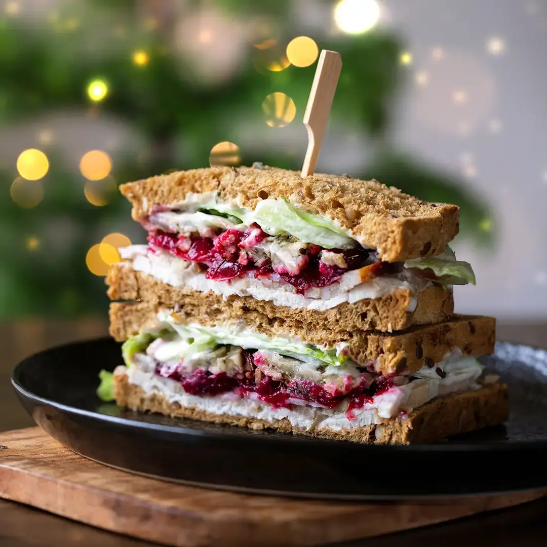 A Nimble® Wholemeal sandwich filled with thin slices of leftover turkey, lettuce, a few slices of cucumber, tomato and mayonnaise, with some Christmas lights.