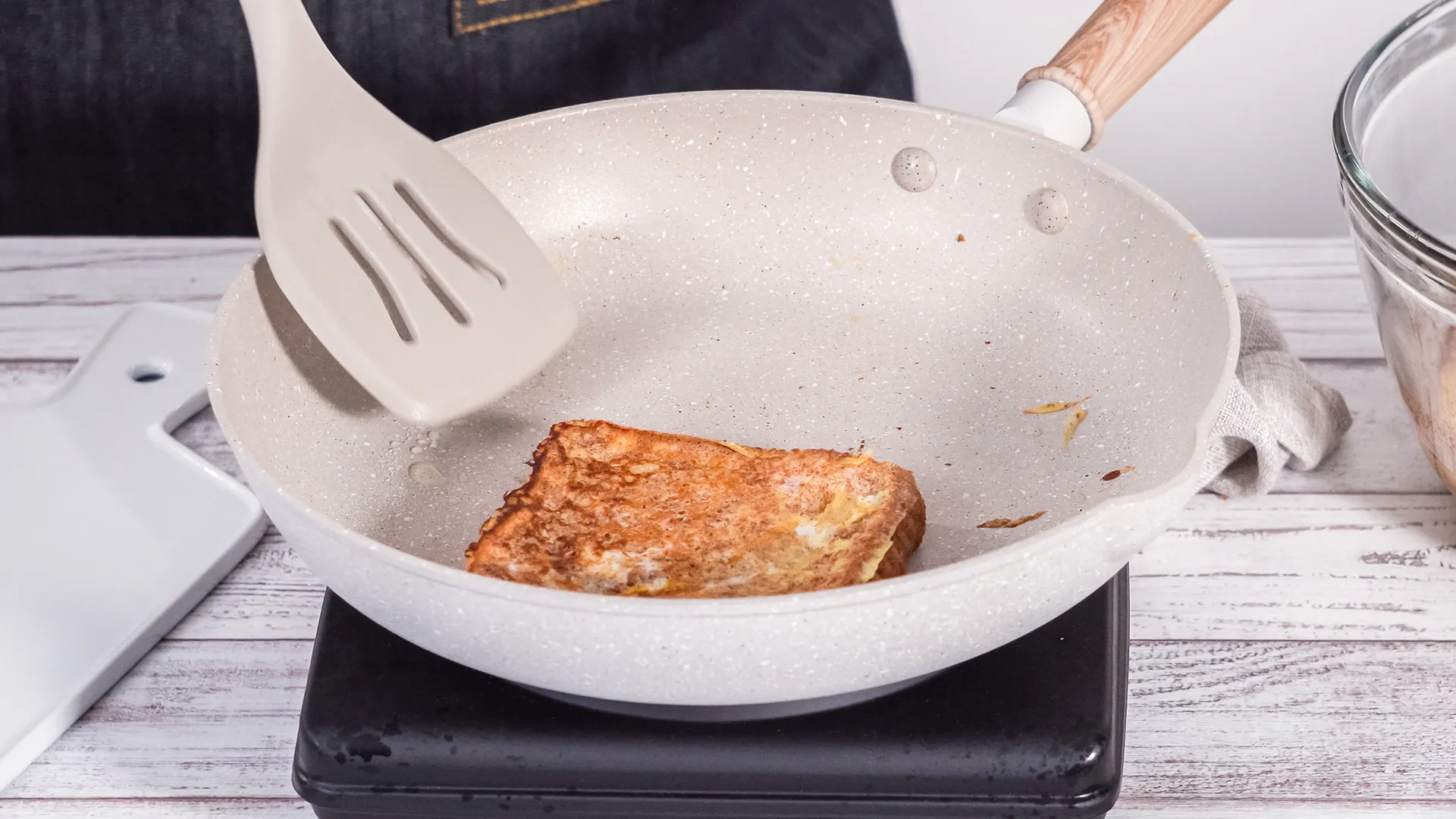 Theres a bowel of mixture of eggs, milk, sugar, vanilla, and cinnamon on the left and on the right a pile of extra slices of bread are stacked.